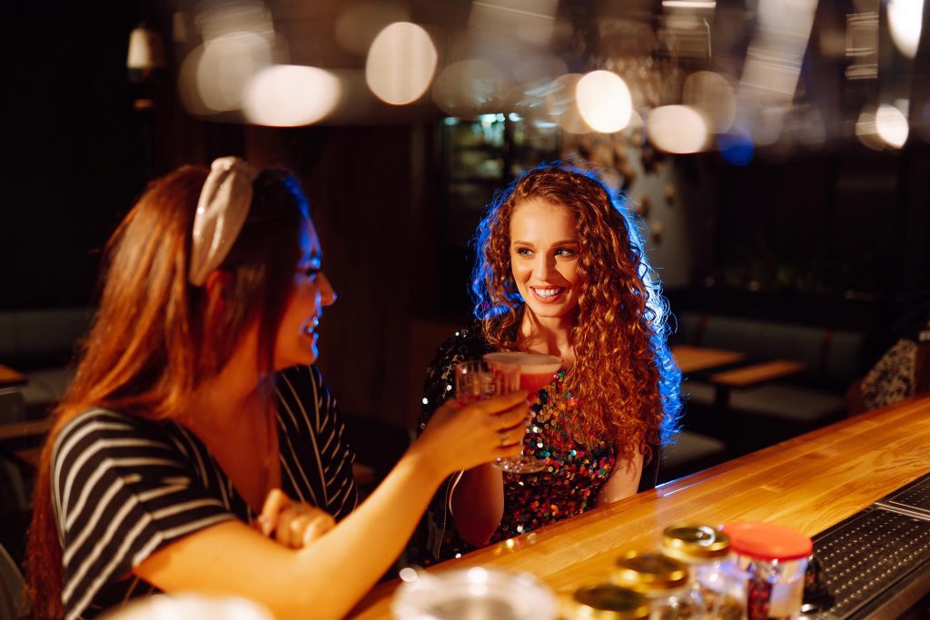 Young woman drinking cocktails in bar.