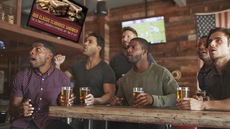 Men Watching sports with ad behind them