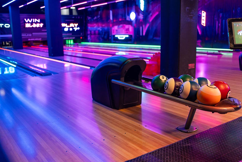 Bowling lane lit up with balls on a rack