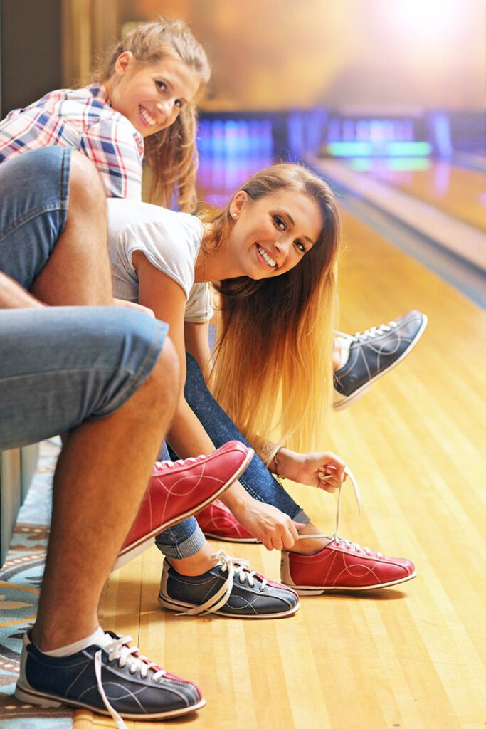 Friends putting on bowling shoes