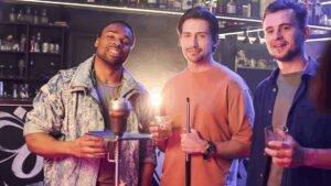 Friends casually standing in front of a bar, one holding a pool cue